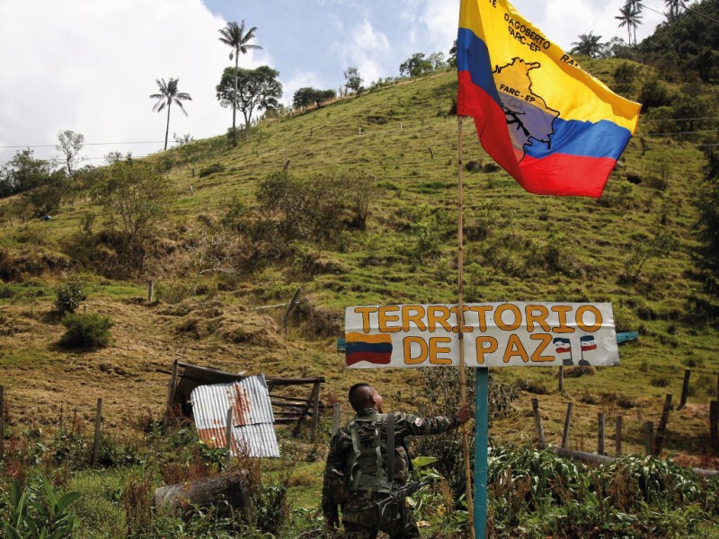 A rebel of the dissident Revolutionary Armed Forces of Colombia stands next to a flag during the release of hostage and Colombian Army soldier Juan David Estrada, in Tacueyo, southwest Colombia, Tuesday, Sept. 26, 2023. Estrada was handed over to a delegation of the International Red Cross as a peace gesture to the government of Colombia. (AP Photo/Andres Quintero)